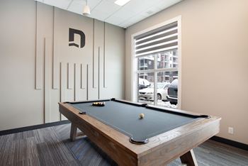 A pool table in a room with a window showing a parking lot outside.